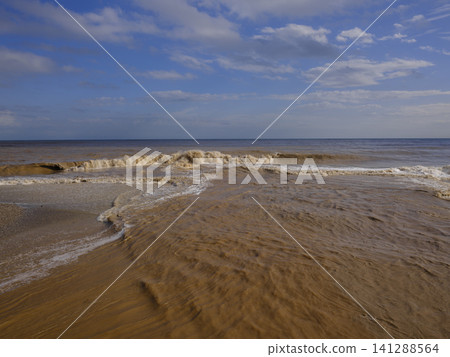 Flooded brown river flowing into sea 141288564
