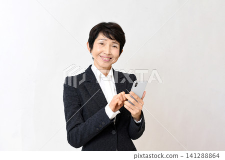 一位面帶微笑的亞洲老年女性手持智慧型手機。 一位面帶微笑的亞洲老年女性手持智慧型手機。 141288864