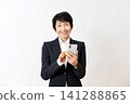 A senior Asian woman smiling while holding her smartphone. 141288865