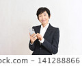 A senior Asian woman smiling while holding her smartphone. 141288866