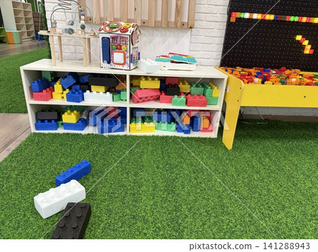 White storage shelves with colorful large building bricks in kids playroom interior with copy space White storage shelves with colorful large building bricks in kids playroom interior with copy space 141288943
