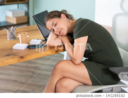 Tired female manager fell asleep at her desk in company office. Tired female manager fell asleep at her desk in company office. 141289182