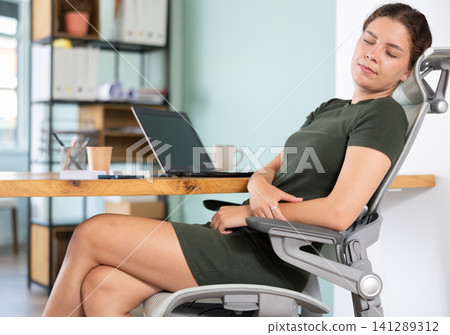 Young woman in dress sleeping sitting at office desk Young woman in dress sleeping sitting at office desk 141289312