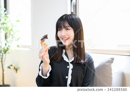 Japanese woman eating donuts in bed Japanese woman eating donuts in bed 141289380