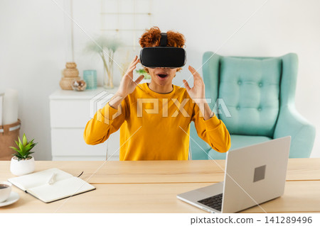 African American young woman wearing using virtual reality metaverse VR glasses headset at home. Girl touching air during VR experience on virtual reality helmet. Simulation hi-tech videogame concept African American young woman wearing using virtual reality metaverse VR glasses headset at home. Girl touching air during VR experience on virtual reality helmet. Simulation hi-tech videogame concept 141289496