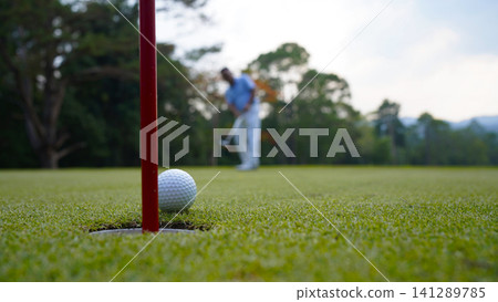 Golfers are putting golf in the evening golf course golf backglound. Golfers are putting golf in the evening golf course golf backglound. 141289785