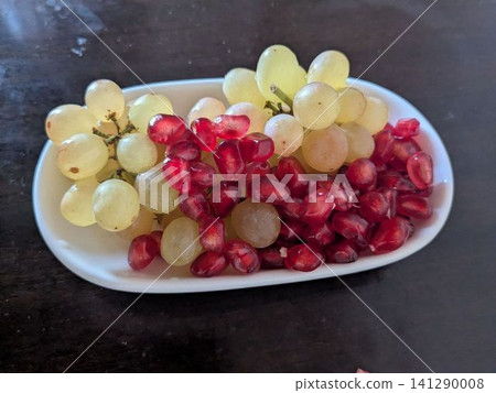 Fresh white grapes and pomegranate seeds on a white plate Fresh white grapes and pomegranate seeds on a white plate 141290008