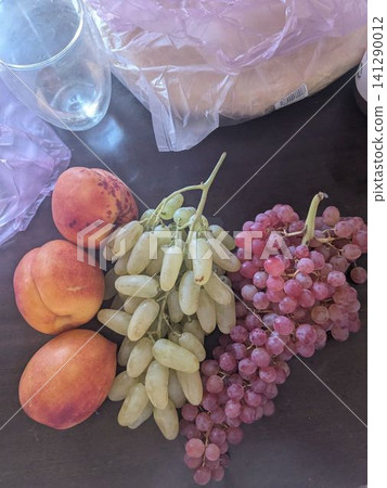 Fresh peaches and grapes rest on a dark surface Fresh peaches and grapes rest on a dark surface 141290012