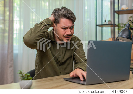 Middle-aged man frowning laptop frustrated by error bad news virus warning stressful work at table Middle-aged man frowning laptop frustrated by error bad news virus warning stressful work at table 141290021