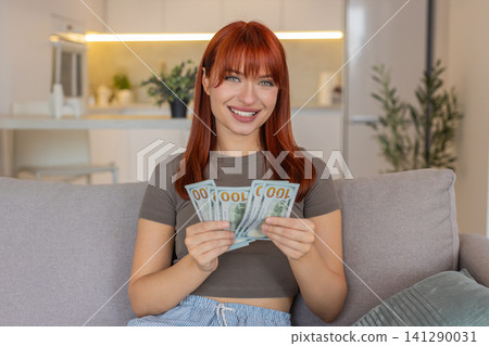Young woman counts cash dollars with smile happy about salary savings plans invest profit big growth Young woman counts cash dollars with smile happy about salary savings plans invest profit big growth 141290031