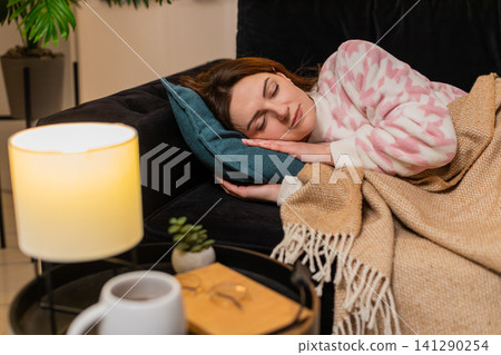 Adult woman exhausted after hard work day lies down on pillow closes eyes falls asleep at night calm Adult woman exhausted after hard work day lies down on pillow closes eyes falls asleep at night calm 141290254