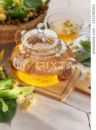 Linden tea brewing in glass teapot with lime blossom Linden tea brewing in glass teapot with lime blossom 141290301
