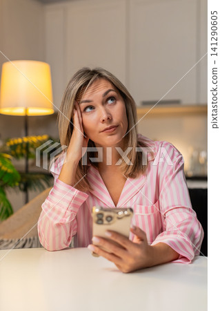 Adult woman scrolls news on smartphone bored tired stressed demotivated seeks calm break at night Adult woman scrolls news on smartphone bored tired stressed demotivated seeks calm break at night 141290605