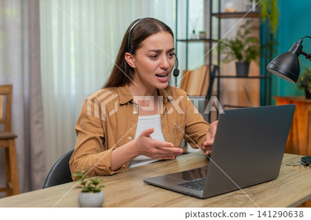 Young woman angry on laptop headset chat venting frustration shows intense tension during support 141290638