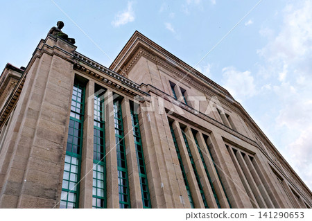 Architectural low angle view of a classic stone public building facade with roof statue Architectural low angle view of a classic stone public building facade with roof statue 141290653