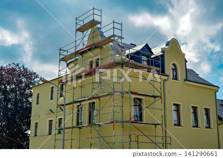 Historic yellow mansion under renovation covered with tall metal scaffolding structures Historic yellow mansion under renovation covered with tall metal scaffolding structures 141290661