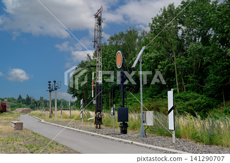 Vintage mechanical railway signals and poles along path next to forest Vintage mechanical railway signals and poles along path next to forest 141290707