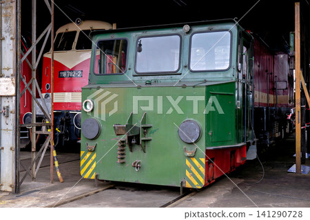 Small green vintage shunting locomotive engine inside an old railway depot hangar Small green vintage shunting locomotive engine inside an old railway depot hangar 141290728