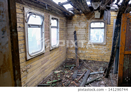 Destroyed interior of an old train car with yellow walls and a collapsed ceiling Destroyed interior of an old train car with yellow walls and a collapsed ceiling 141290744
