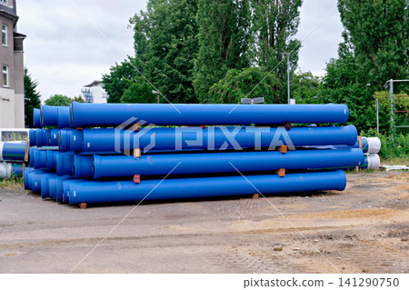 Long blue plastic plumbing pipes stacked at outdoor building site Long blue plastic plumbing pipes stacked at outdoor building site 141290750
