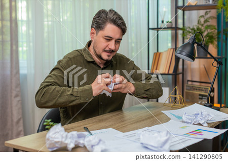Middle-aged man crumples paper throws aside upset by report mistake frustrated angry at table desk Middle-aged man crumples paper throws aside upset by report mistake frustrated angry at table desk 141290805