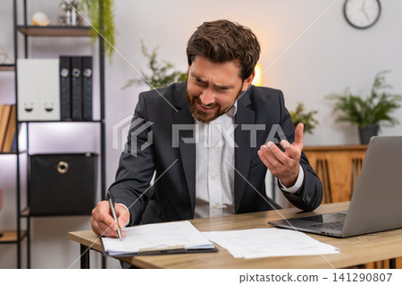 Middle-aged businessman lawyer reviews contracts finds mistake facepalm then corrects with pen fast Middle-aged businessman lawyer reviews contracts finds mistake facepalm then corrects with pen fast 141290807