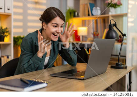 Young woman on home table celebrating success after good laptop news feeling joy and victory indoors Young woman on home table celebrating success after good laptop news feeling joy and victory indoors 141290812