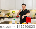 Asian man in kitchen pours glass of milk and drinks protein rich drink for healthy muscle growth fit 141290823