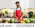 Arabian young adult man cutting tomatoes for salad in kitchen preparing healthy fitness meal at home 141290824