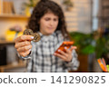 Young woman on home table feeling worried about bitcoin loss while checking smartphone as investor 141290825
