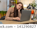 Young woman sits at laptop leans on hand looks so sad unmotivated to continue work emotional burnout 141290827
