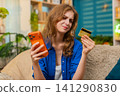 Young woman on home sofa checks failed payment on smartphone holding bank card and feeling worried 141290830