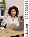 African American businesswoman waves hello toward laptop camera smiling friendly hi greeting gesture 141290841