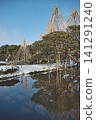 Kenrokuen Garden in winter, where the beautiful reflection of snow-covered trees is visible on the calm surface of the water. 141291240