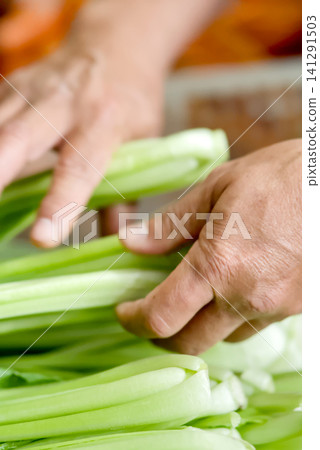 resh vegetables for sale at a local market stall, featuring carrots in a white plastic crate and leafy greens in the background resh vegetables for sale at a local market stall, featuring carrots in a white plastic crate and leafy greens in the background 141291503