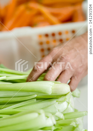 resh vegetables for sale at a local market stall, featuring carrots in a white plastic crate and leafy greens in the background	 141291504