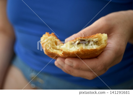 Closeup of a hand holding a bitten chocolate pastry with a soft blurred background. Fresh baked breakfast pastry enjoyed as a snack or morning treat. Closeup of a hand holding a bitten chocolate pastry with a soft blurred background. Fresh baked breakfast pastry enjoyed as a snack or morning treat. 141291681