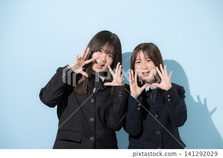 身穿校服的國中和高中女生站在淺藍色背景前,微笑著看著鏡頭;評論和鼓勵的留言。 身穿校服的國中和高中女生站在淺藍色背景前,微笑著看著鏡頭;評論和鼓勵的留言。 141292029