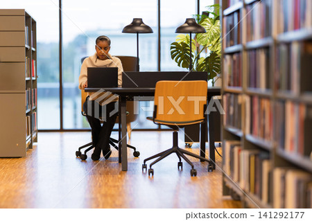 Student focused on work in library 141292177