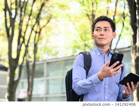 A man holding a smartphone in a park A man holding a smartphone in a park 141292406