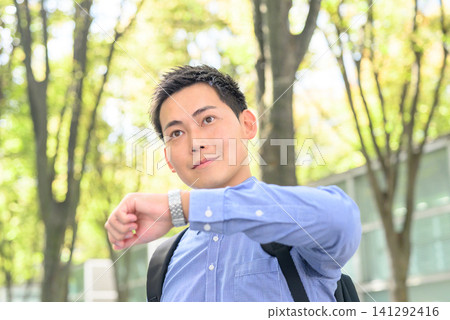 一位商人沐浴在斑駁的陽光下看了看手錶。 141292416