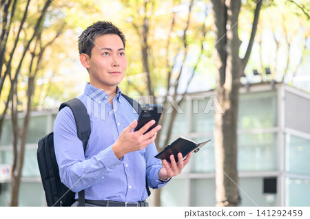 一個男人拿著智慧型手機和筆記型電腦。 一個男人拿著智慧型手機和筆記型電腦。 141292459