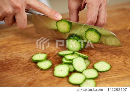 Chef hands slicing fresh cucumber on cutting board Chef hands slicing fresh cucumber on cutting board 141292507
