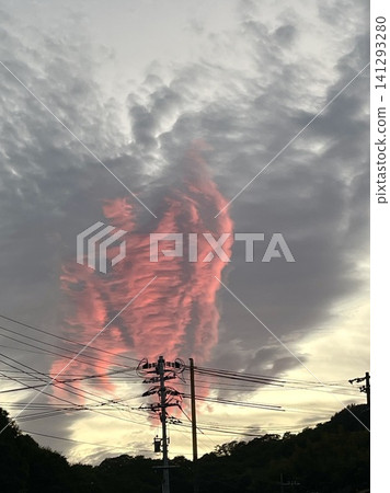 A strange red cloud towering like a giant, and the silhouette of a telephone pole. A strange red cloud towering like a giant, and the silhouette of a telephone pole. 141293280