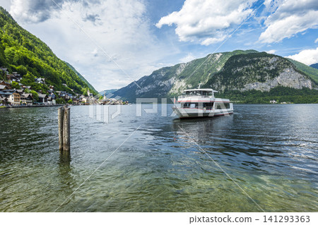 Passenger boat cruising on Lake Hallstatt with mountain landscape in Austria, illustrating scenic summer tourism in Europe. 141293363