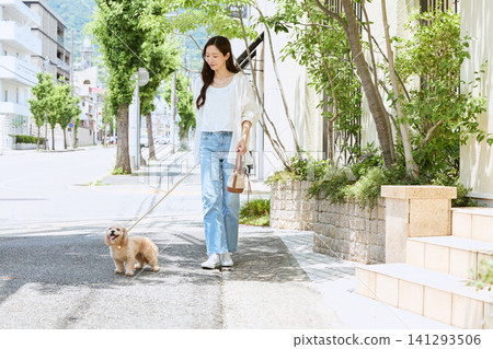 A young woman walks her dog through the lush green streets. A young woman walks her dog through the lush green streets. 141293506