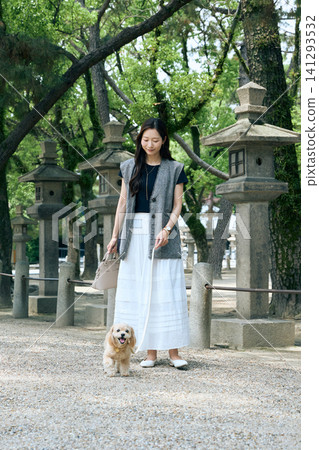 A smiling woman walks her dog along the shrine's approach lined with stone lanterns. A smiling woman walks her dog along the shrine's approach lined with stone lanterns. 141293532