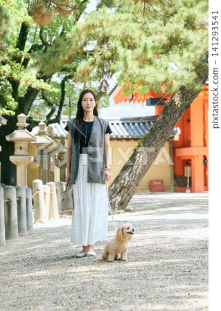 A young woman walking her dog in the grounds of a shrine. A young woman walking her dog in the grounds of a shrine. 141293541