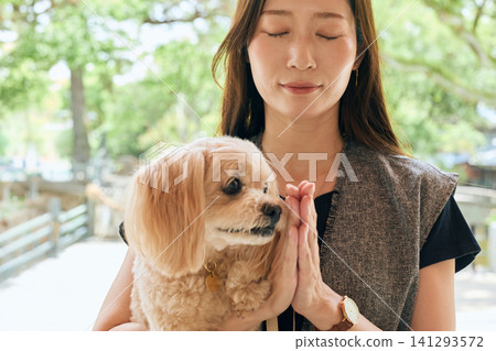 一名女子抱著她的狗在神龕前祈禱。 一名女子抱著她的狗在神龕前祈禱。 141293572