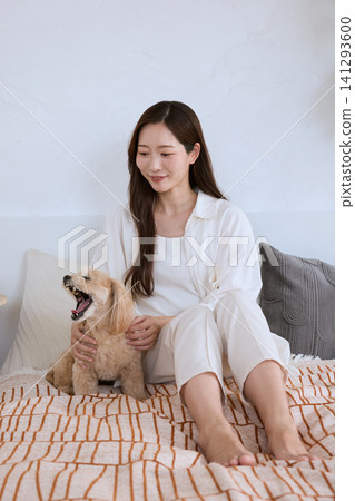 A young woman with a smile relaxing on the living room sofa with her dog. A young woman with a smile relaxing on the living room sofa with her dog. 141293600